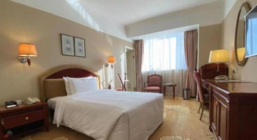 a hotel room with a large bed and a desk at Jianguo Garden Hotel in Beijing
