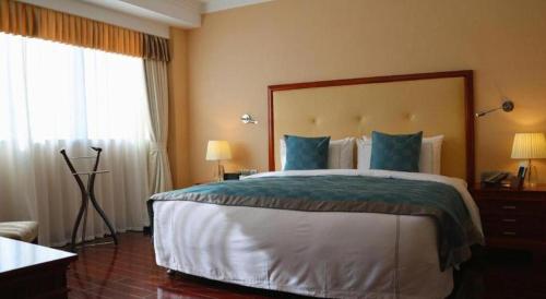 a hotel room with a large bed with blue pillows at Jianguo Garden Hotel in Beijing