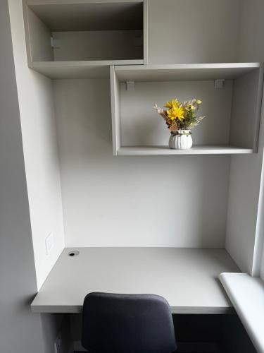 a white desk with a vase of flowers on a shelf at NOI-Apartment in Căuşeni