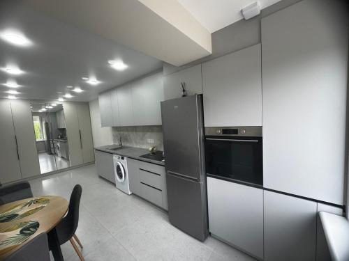 a kitchen with white cabinets and a table and a refrigerator at NOI-Apartment in Căuşeni