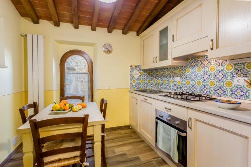 a kitchen with a table with a bowl of fruit on it at Olivo Cottage - Monti 1824 in Casole dʼElsa