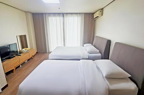 una camera d'albergo con due letti e una televisione di Ilsung Resort Sulak a Goseong
