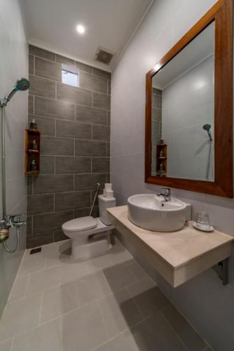 a bathroom with a sink and a toilet and a mirror at HON BA LAGI BEACH RESORT in La Gi