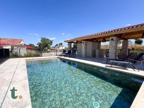 - une piscine dans un jardin avec un kiosque dans l'établissement Tranquiloue - La Maison de Gabriel - Puy du Fou, aux Herbiers