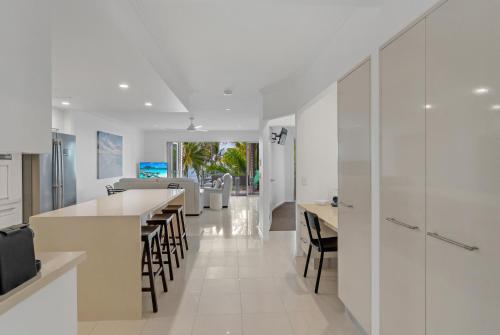 a kitchen with white walls and tables and chairs at Rojo at Island Views—A Breezy Beachfront Retreat in Palm Cove
