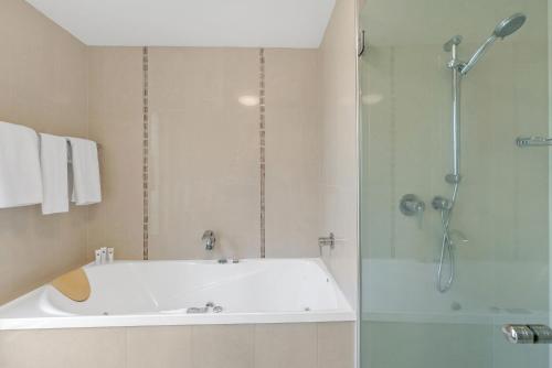 a bathroom with a tub and a shower and a sink at Rojo at Island Views—A Breezy Beachfront Retreat in Palm Cove