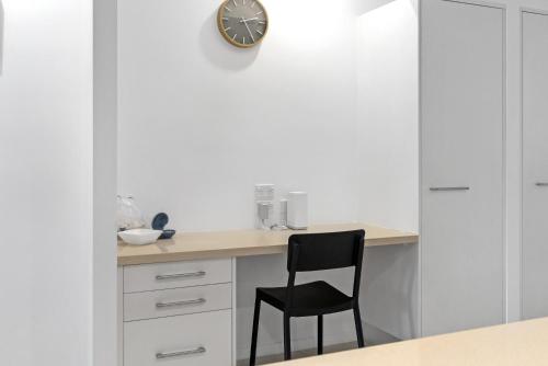 a desk with a chair and a clock on a wall at Rojo at Island Views—A Breezy Beachfront Retreat in Palm Cove