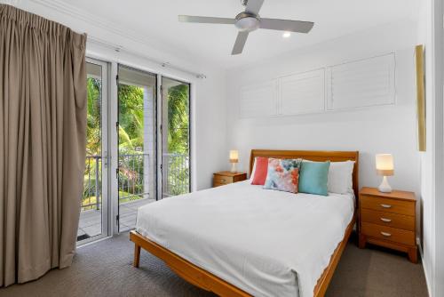 a white bedroom with a bed and a balcony at Rojo at Island Views—A Breezy Beachfront Retreat in Palm Cove