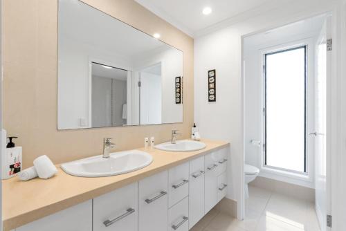 a white bathroom with two sinks and a mirror at Rojo at Island Views—A Breezy Beachfront Retreat in Palm Cove