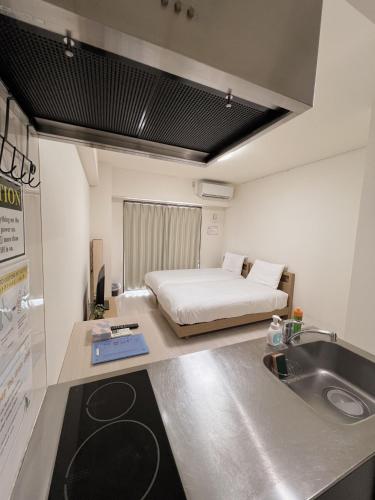 a room with a bed and a sink and a kitchen at CIEL BLEU in Tokyo