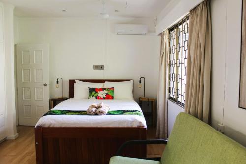 a bedroom with a bed and a green chair at Residence71Nadi Fiji in Nadi