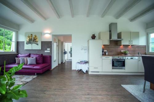 a living room with a purple couch and a kitchen at Gartenhof in Brixen