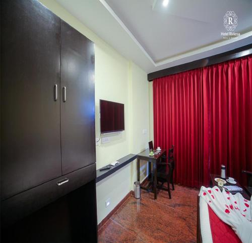 a hotel room with a desk and a red curtain at RivieraaHotel in Pondicherry