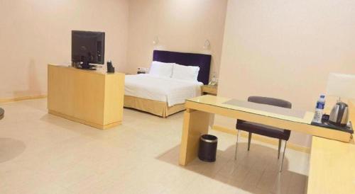 a bedroom with a bed and a desk with a television at The Bauhinia in Shenzhen