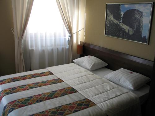 a bed with two pillows in a bedroom with a window at Hotel Stari grad in Jajce