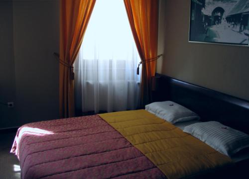 a bedroom with a bed with a yellow blanket and a window at Hotel Stari grad in Jajce
