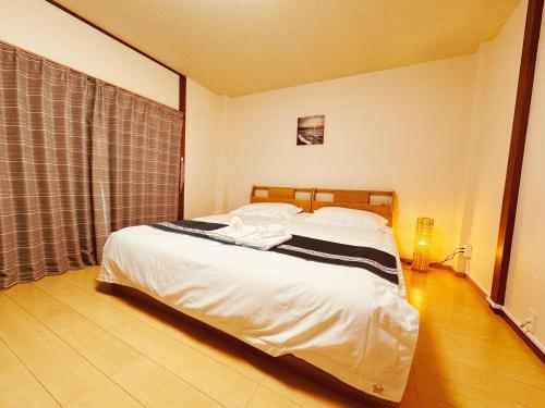 a bedroom with a bed with a black and white blanket at Osaka Castle Park Station, 10 minutes walk to Kyobashi Station, direct access to Shinsaibashi, Umeda, Kansai Airport, Kyoto, Nara, USJ, can accommodate up to 10 people in Wada