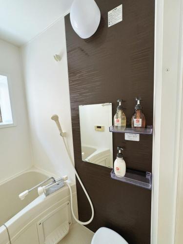a bathroom with a white toilet and a mirror at Osaka Castle Park Station, 10 minutes walk to Kyobashi Station, direct access to Shinsaibashi, Umeda, Kansai Airport, Kyoto, Nara, USJ, can accommodate up to 10 people in Wada