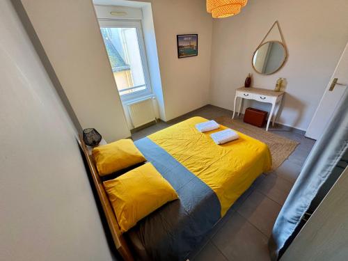 1 dormitorio con 1 cama con sábanas amarillas y espejo en Bel appartement de 105m2 VUE RIA d'ETEL, en Étel