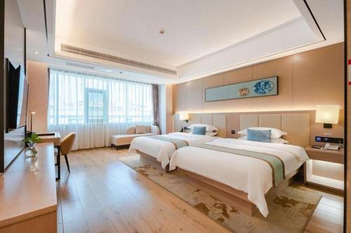 a large hotel room with two beds and a television at GreenTree Eastern Dali Railway Station Hotel in Dali