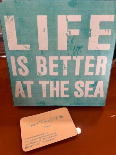 a sign that says life is better at the sea at Hotel De La Ville in Rimini