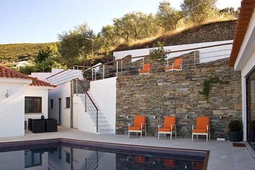 a patio with orange chairs next to a stone wall at Phenomenal Pinhao Villa 3 Bedrooms Villa Douroco Beautiful Valley Views Pool Table in Pinhão