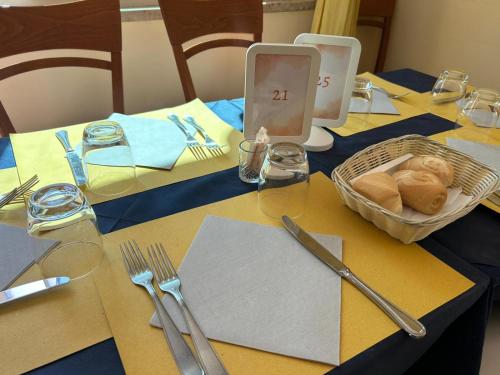 a table with a cell phone and a basket of bread at Hotel De La Ville in Rimini