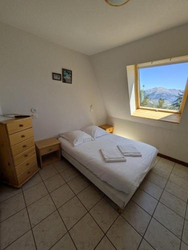 a bedroom with a white bed and a window at Auberge de Pra-Loup in Pra-Loup