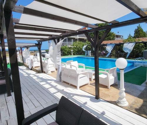 a patio with white furniture and a swimming pool at Complex Exotica in Lozenets