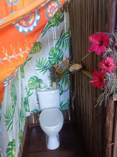 a toilet in a bathroom with flowers on the wall at La Maison de Morgana in Bemoko