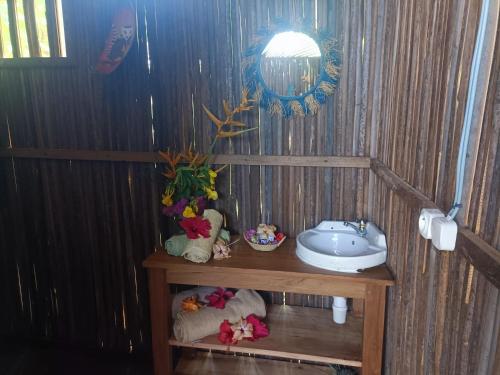 a bathroom with a sink in a wooden wall at La Maison de Morgana in Bemoko