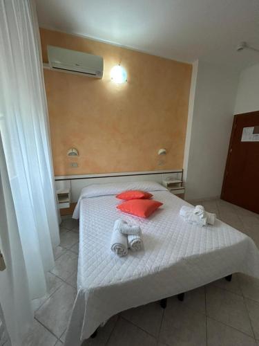 a bedroom with a white bed with red pillows at Hotel De La Ville in Rimini