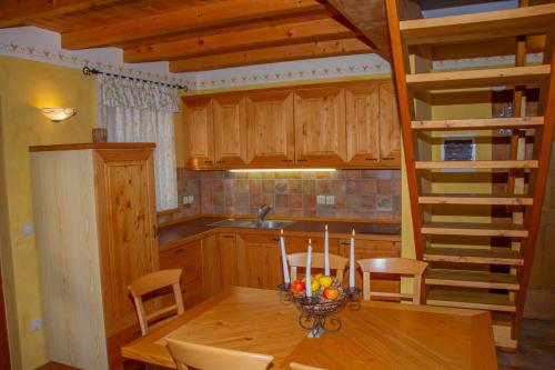 a kitchen with a wooden table and a wooden spiral staircase at Zidanica Krošelj in Raka