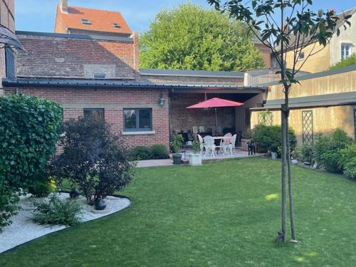 patio con mesa y sombrilla en STUDIO VOYAGE COLONIAL CLIMATISE chic, en Beauvais