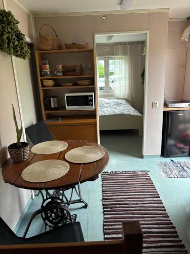 a kitchen with a table and a room with a bed at Namiņš in Ragaciems