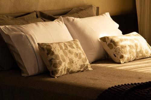 a bed with white pillows and brown and white pillows at Windows House in Paty do Alferes