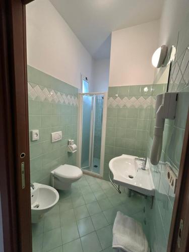 a bathroom with two sinks and a toilet and a shower at Hotel De La Ville in Rimini