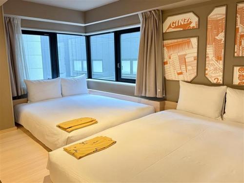 two beds in a room with windows at lyf Ginza Tokyo in Tokyo