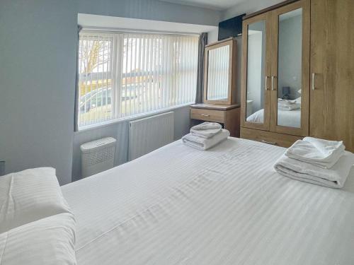 a bedroom with a large white bed with towels on it at Driftwood in Sutton on Sea