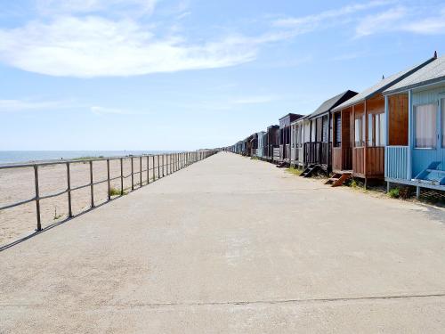 a long sidewalk next to the beach with houses at Driftwood in Sutton on Sea