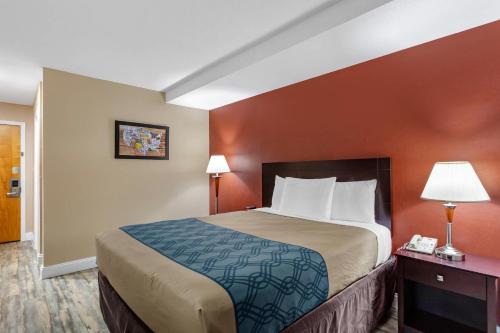 a hotel room with a large bed with orange walls at Econo Lodge Inn & Suites Old Saybrook - Westbrook in Old Saybrook