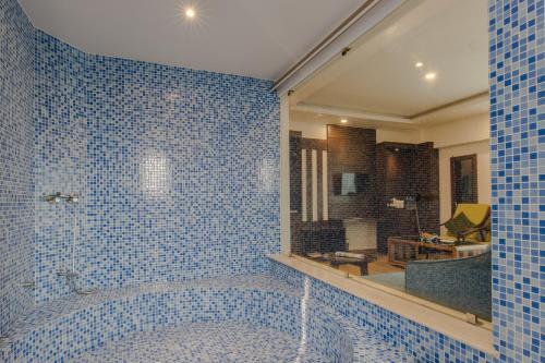a blue tiled bathroom with a tub with a mirror at Mourya Hotel in Bhairāhawā