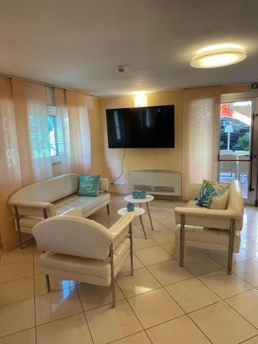 a living room with couches and a flat screen tv at Hotel De La Ville in Rimini