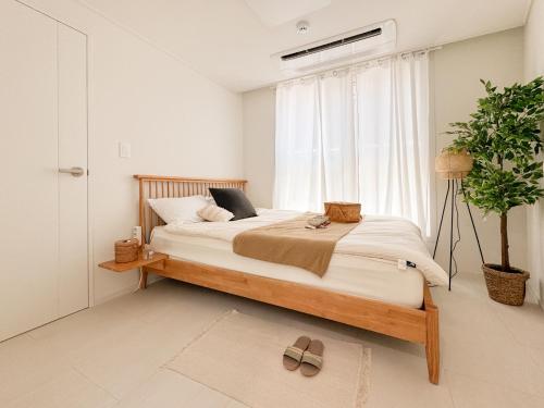 a bedroom with a large bed and a potted plant at 3-Min Walk from Achasan Station, 2-Bedroom Bali Mood Stay with Hinoki Aroma in Seoul