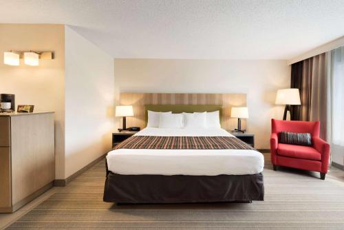 a hotel room with a bed and a red chair at Country Inn & Suites by Radisson, Chippewa Falls, WI in Chippewa Falls