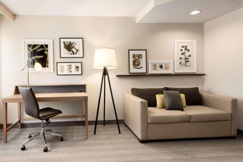 a living room with a couch and a desk and a lamp at Country Inn & Suites by Radisson, Chippewa Falls, WI in Chippewa Falls
