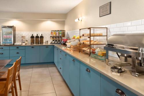 a kitchen with blue cabinets and a counter with food at Country Inn & Suites by Radisson, Chippewa Falls, WI in Chippewa Falls