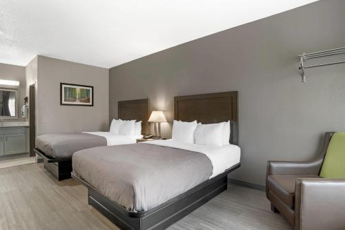 a hotel room with two beds and a chair at Quality Inn Simpsonville-Greenville in Simpsonville