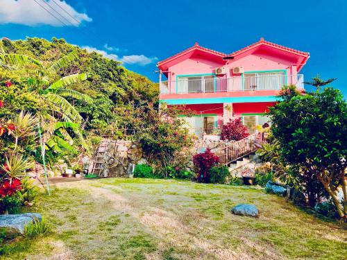 a pink house on top of a hill at ペンション波 in Ufugumui