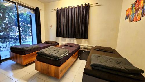 a room with three beds and a window at Rostel Backpackers Hostel in Pune
